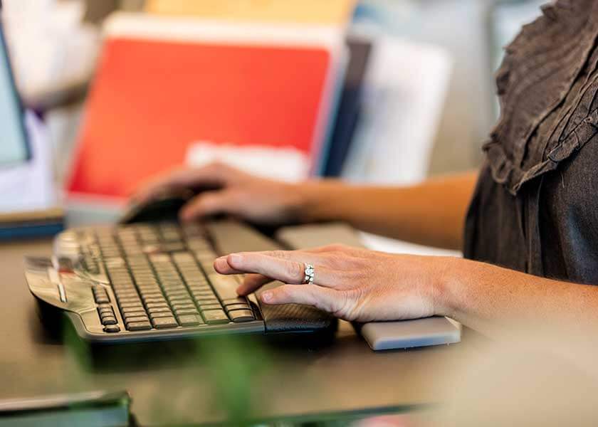 A person using a computer sitting on top of a desk